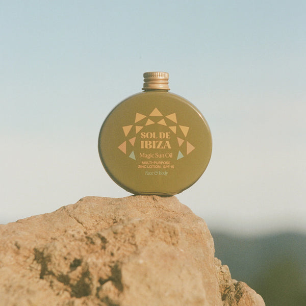 Green bottle labeled 'Sole de Ibiza' on a rock with a blurred natural background