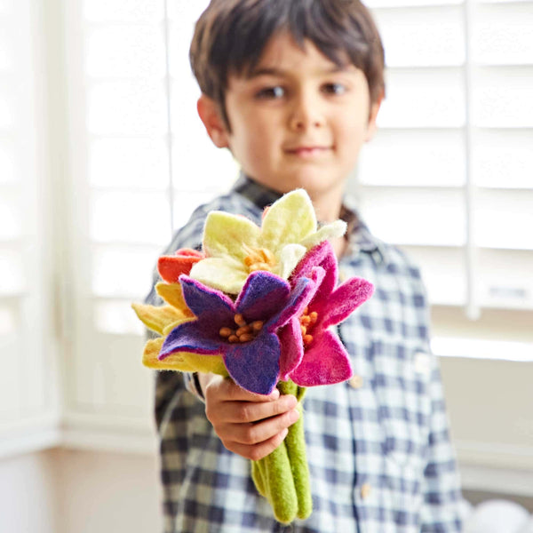 Child holding a colourful felt flower bouquet indoors