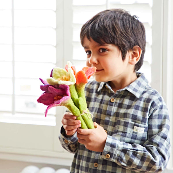 Child holding colourful felt flowers in front of a window