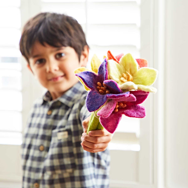 Child holding a bouquet of colourful felt flowers in front of a white background