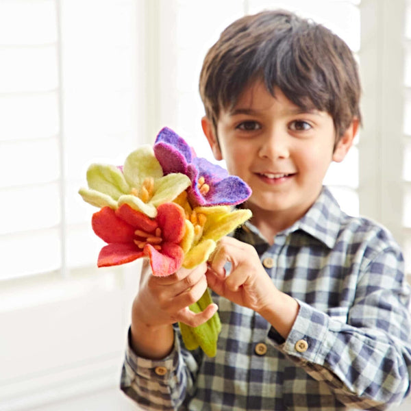 Child holding a bouquet of colourful felt flowers indoors