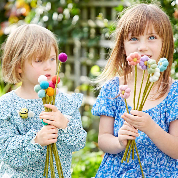 Two children holding colourful flower bouquets outdoors.