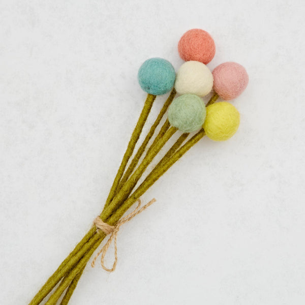 Bouquet of felted wool flowers with colourful pom poms on a white background