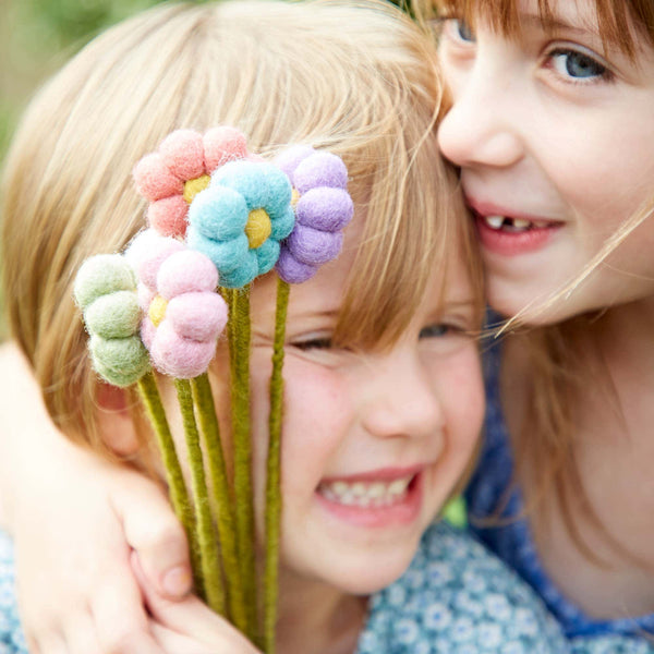 Two children holding a bouquet of colourful flowers outdoors