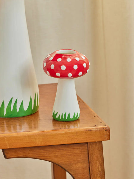 Mushroom-shaped decorative item with red cap and white spots on a wooden surface.