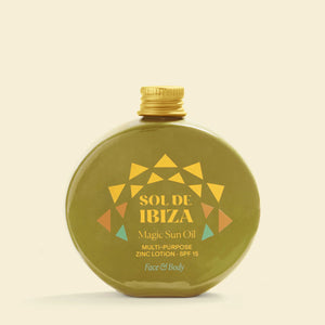Green bottle of Sol de Ibiza Magic Sun Oil with gold cap on a beige background