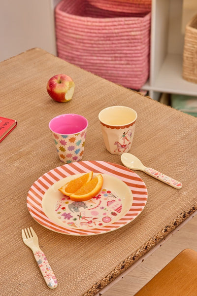 Children's tableware set with cups, plate, fork, and spoon on a textured surface.