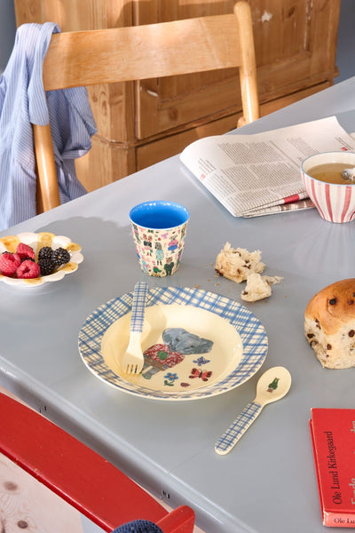Table setting with plates, cups, and food on a gray surface.