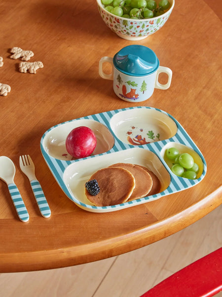 Children's plate with pancakes, fruit, and a cup on a wooden table