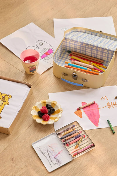 Children's art supplies including crayons, colored pencils, and drawings on a wooden table.