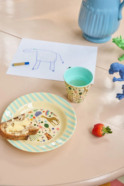 Children's table setting with plate, cup, and toys on a light surface
