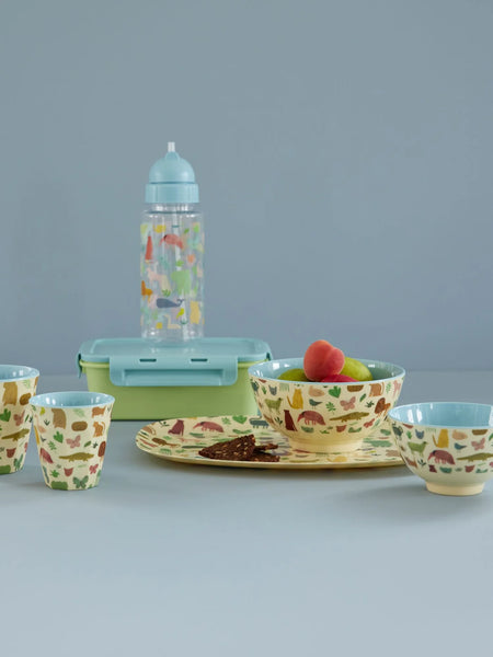 Children's tableware set with cups, bowls, and a bottle on a gray background