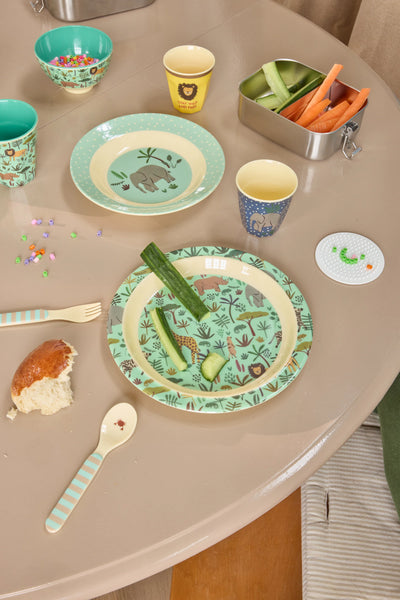 Children's table setting with plates, cups, and snacks on a beige table.