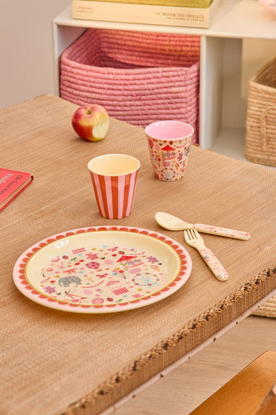 Children's tableware set with plate, cups, and cutlery on a wooden table.