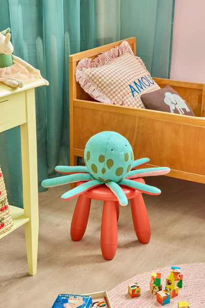 Green octopus soft toy on a red stool in a child's bedroom setting
