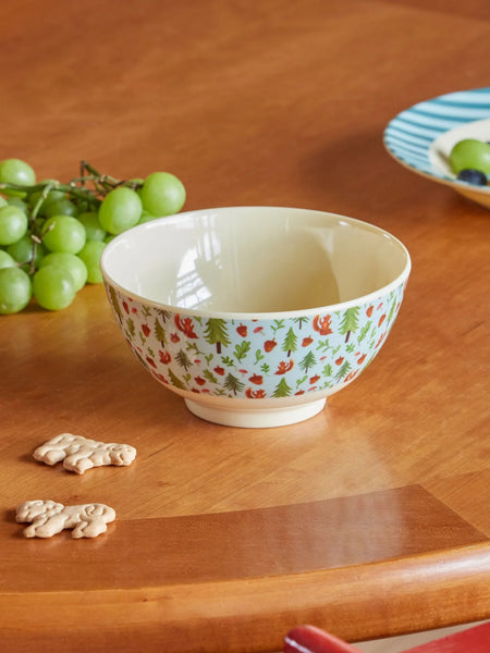 Decorative bowl with a forest pattern on a wooden table with grapes and cookies.