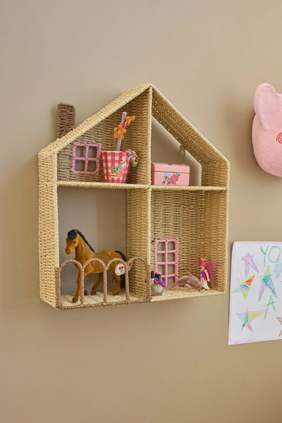Woven house-shaped shelf with toys on a beige wall