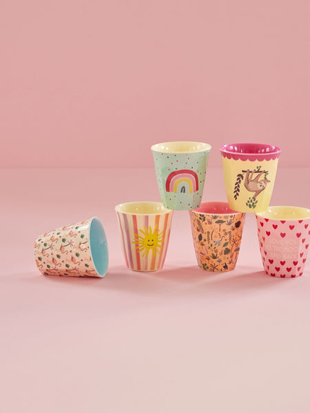 Set of colourful children's cups with various patterns on a pink background