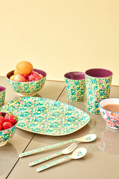 Table setting with yellow floral print cups, bowls and plates