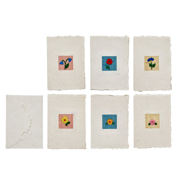 Set of six small greeting cards made from textured white paper with floral designs.