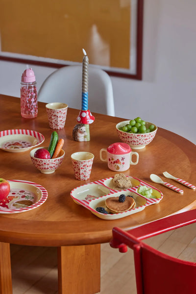Children's play table with miniature food items and tableware on a wooden table.