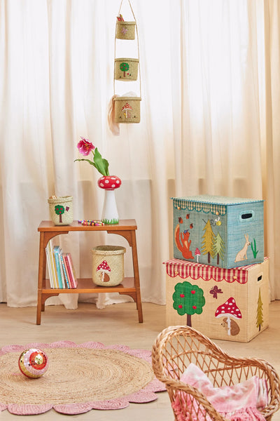 Children's room with storage boxes, books, and a chair in front of white curtains.
