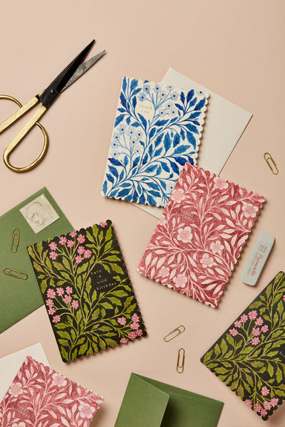 Decorative greeting cards with floral patterns on a beige background with scissors and paper clips.