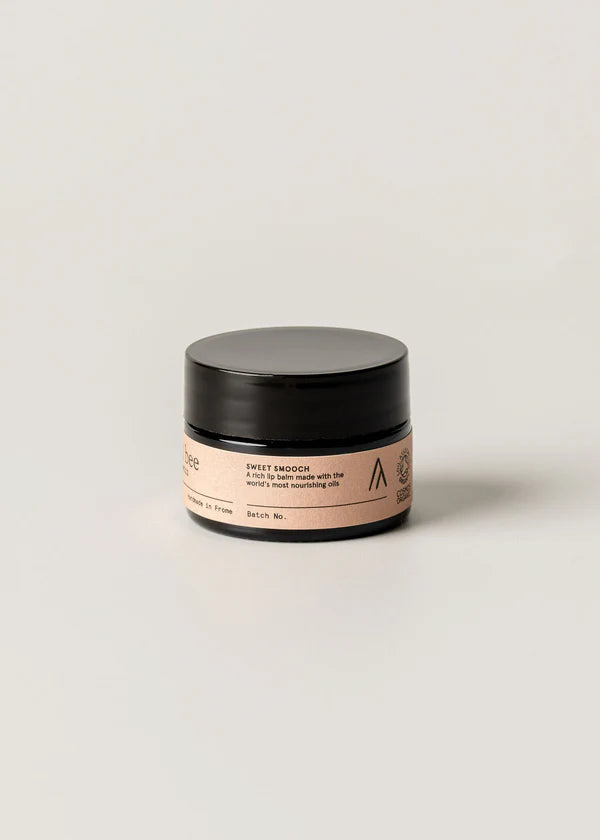 Cosmetic jar with black lid and pink label on a light beige background