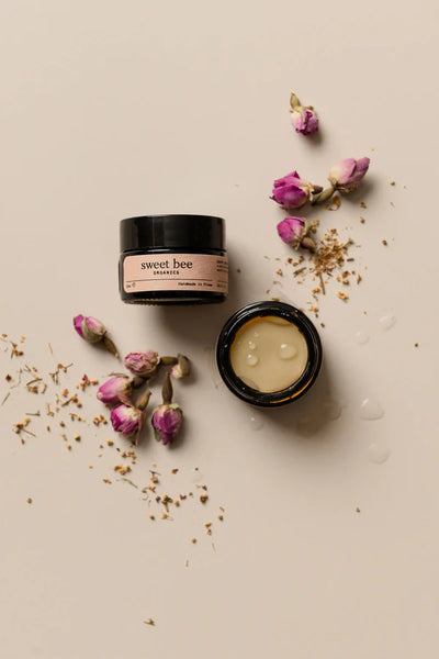 Two jars of 'sweet bee' cream with dried flowers on a beige background