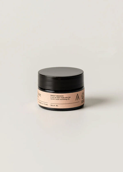 Cosmetic jar with black lid and pink label on a light beige background