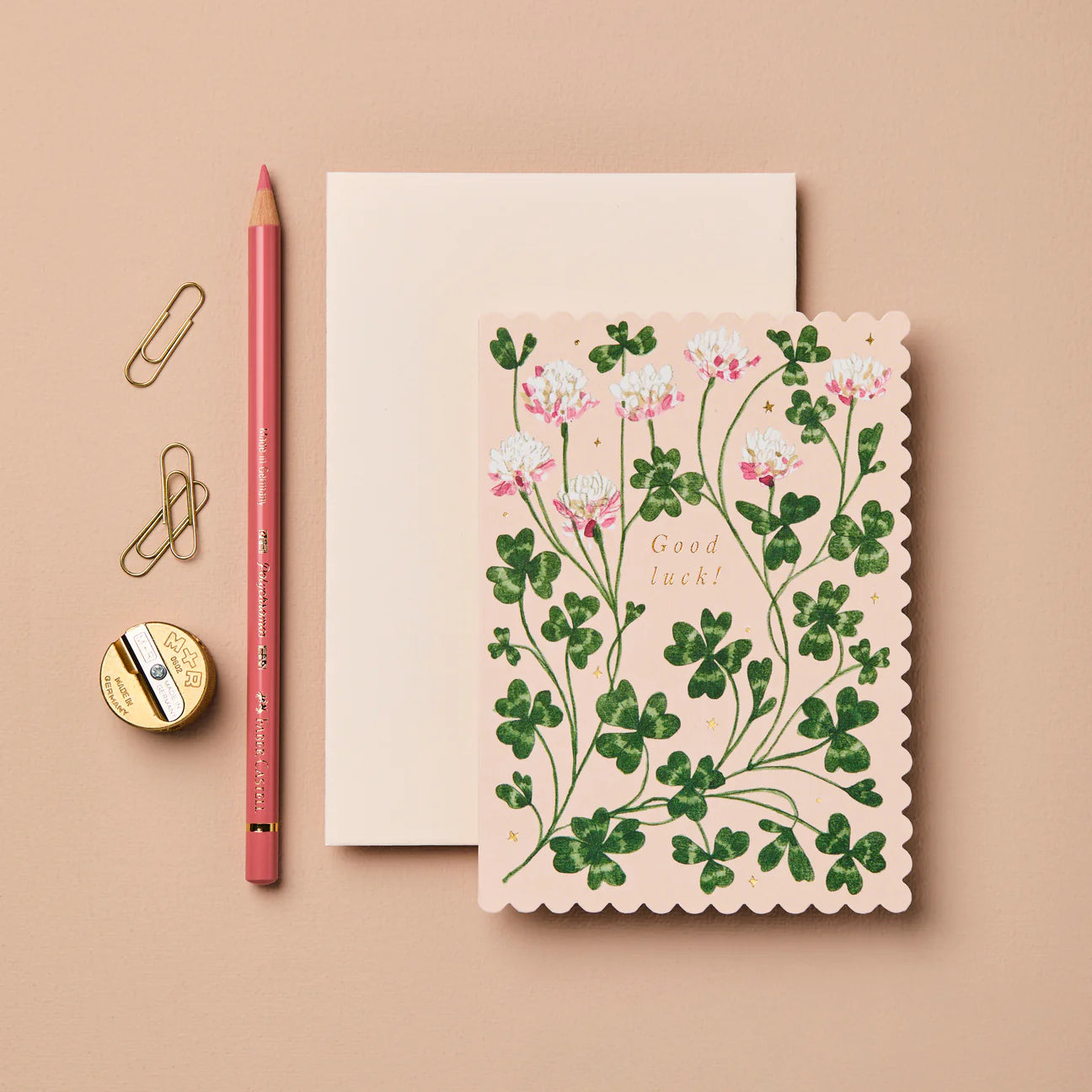 Floral card with 'Good Luck!' text on a beige background with stationery items.