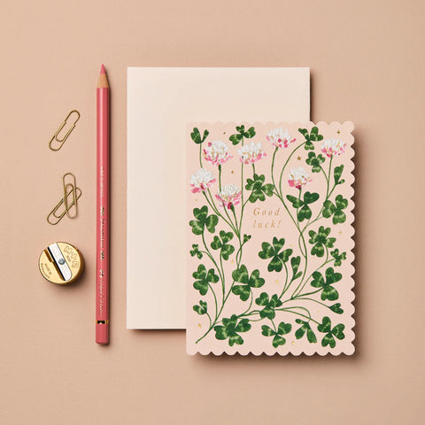 Floral card with 'Good Luck!' text on a beige background with stationery items.