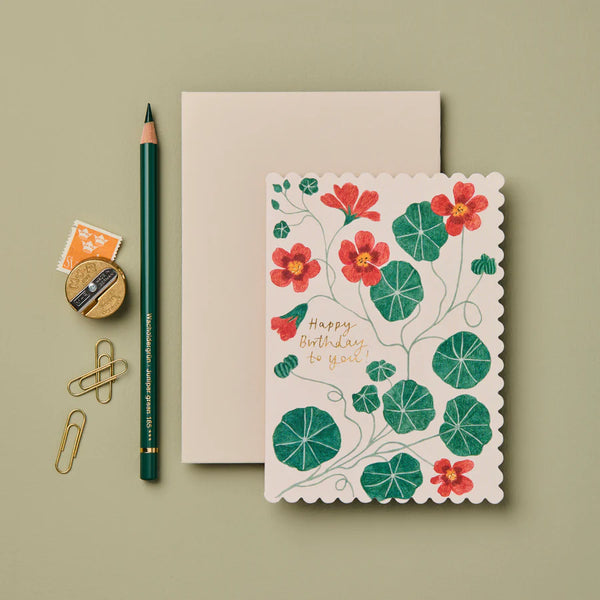 Floral birthday card with stationery items on a green background