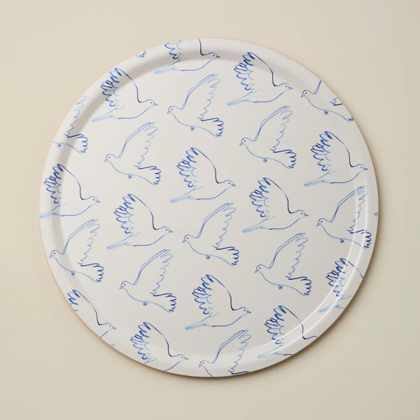 Round tray with blue line art doves against a beige background
