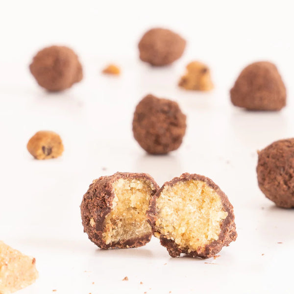 Chocolate truffles with one cut open to reveal a creamy center on a white background