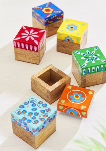 Set of colourful wooden boxes with floral patterned lids on a light background