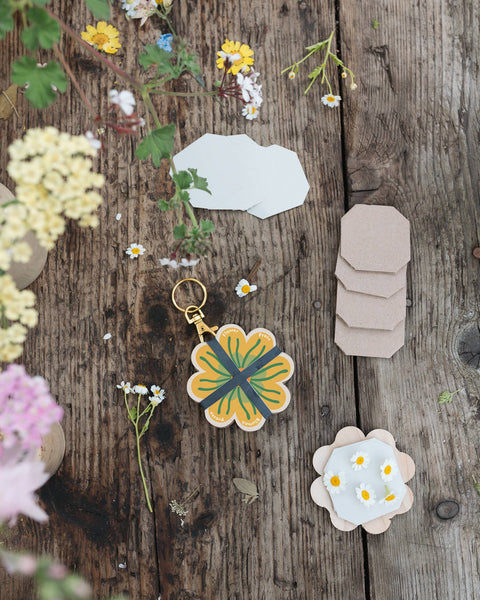 Decorative flower press keychain on a wooden surface with flowers