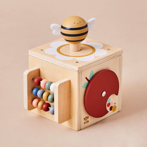 Wooden toy block with bee design and colourful beads on a beige background