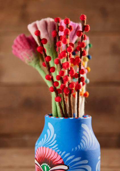 Decorative vase with colorful floral and berry arrangement on a wooden surface