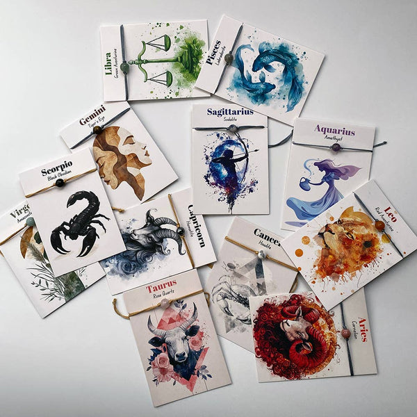 Collection of zodiac-themed cards and bracelets on a light gray background