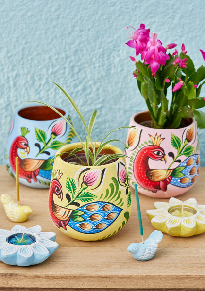 Colourful ceramic pots with floral designs on a wooden surface.