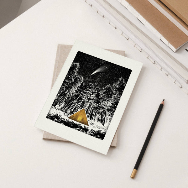 Greeting card of a forest scene with a gold triangular tent and pencil on a white surface