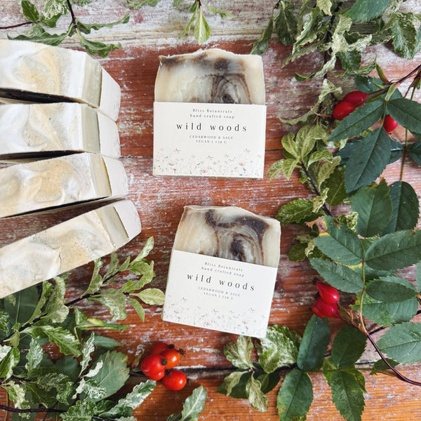 Bar of soap labeled 'wild woods' on a wooden surface with greenery and berries.