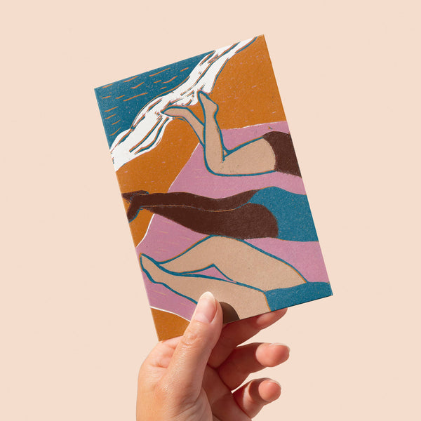 Hand holding a colourful card with abstract design on a beige background