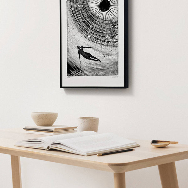 Framed black and white artwork above a wooden table with books and a notebook.