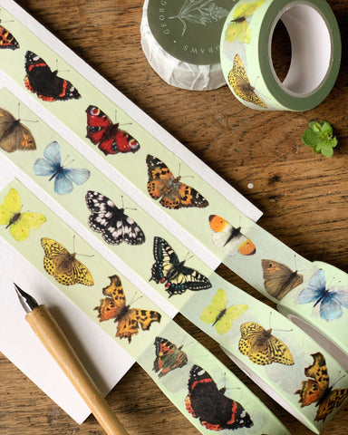 Butterfly-themed washi tape on a wooden surface with a pen.