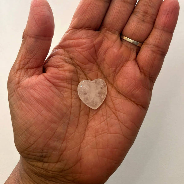 Heart-shaped crystal held in a hand with a plain background