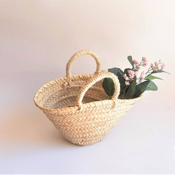 Woven basket with handles containing flowers on a light background