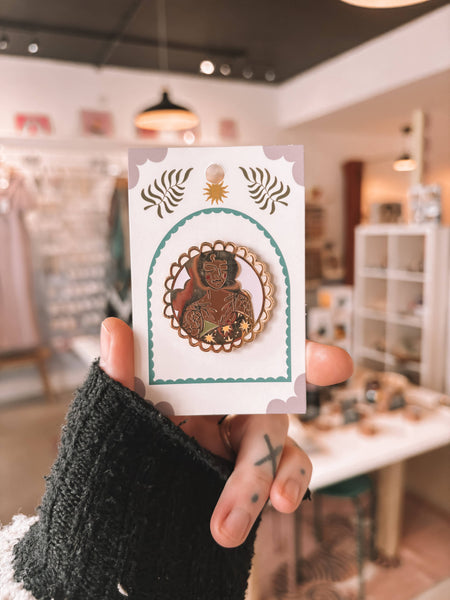 Person holding a card with a decorative pin badge in a store setting