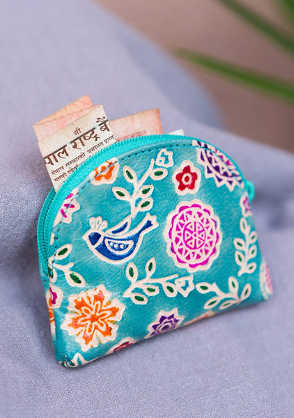 Floral patterned coin purse with currency notes on a light purple background